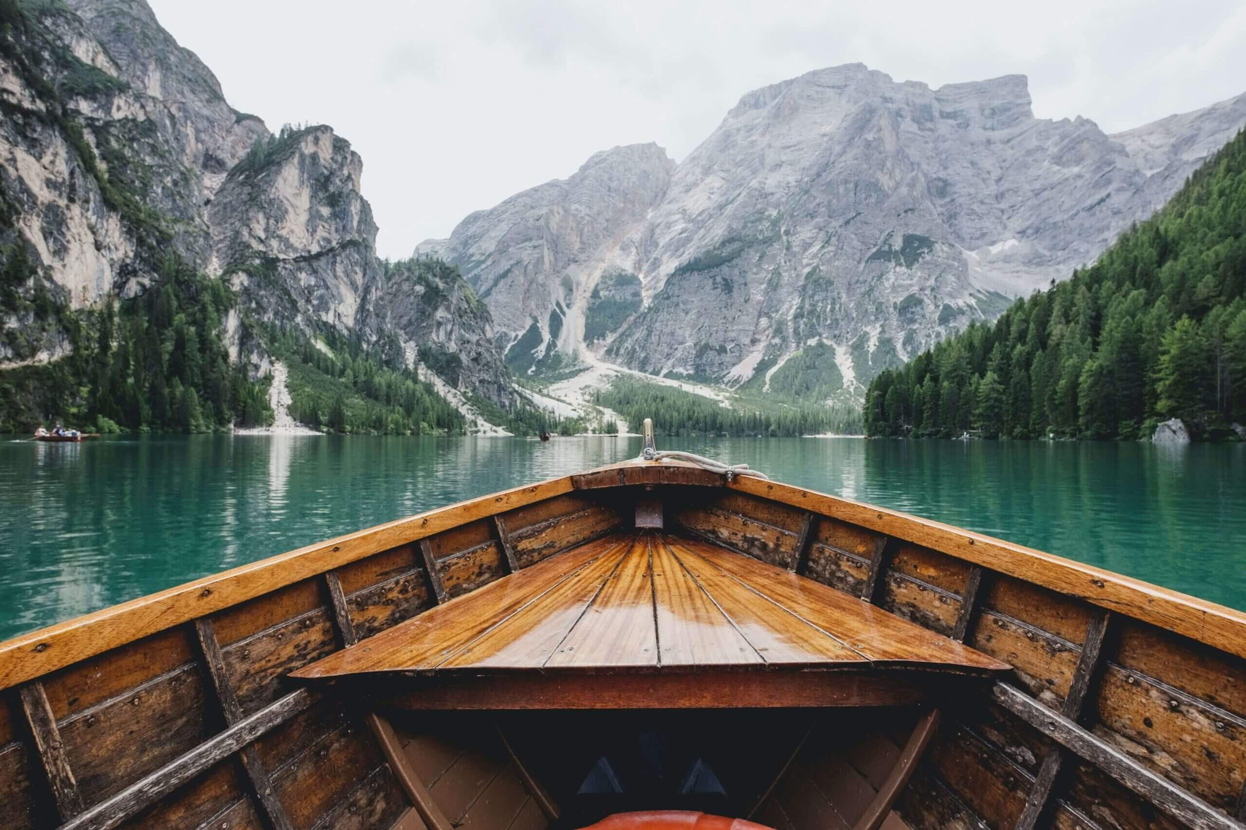 brown boat on green lake toward mountain