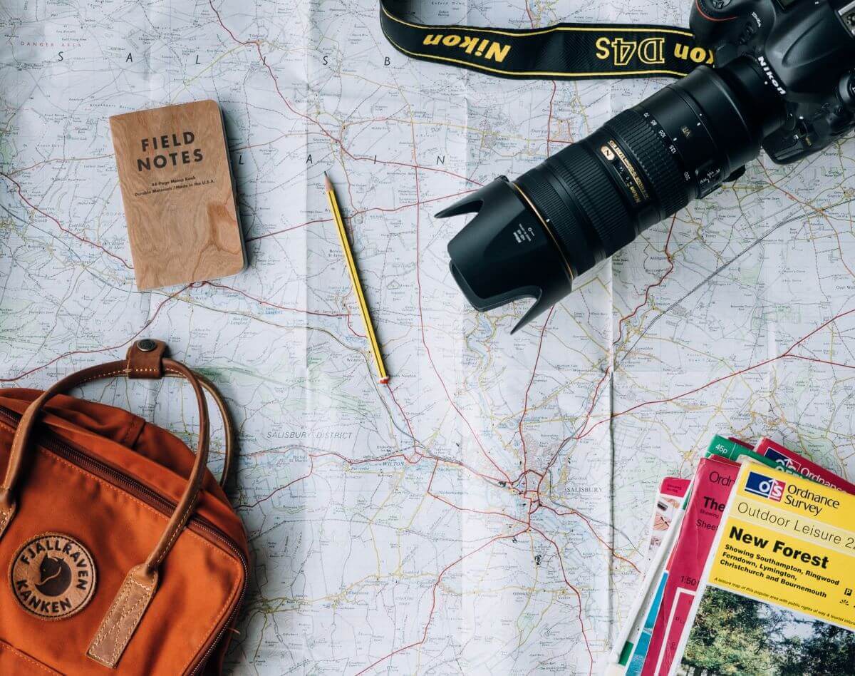 nikon camera notebook on top of a travel map